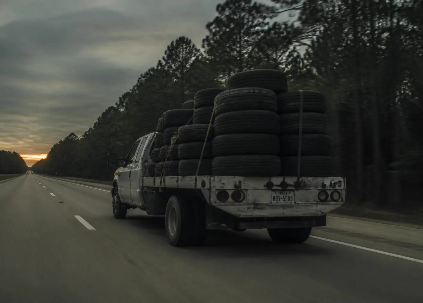 Loaded tire truck driving down a Texas highway at dusk